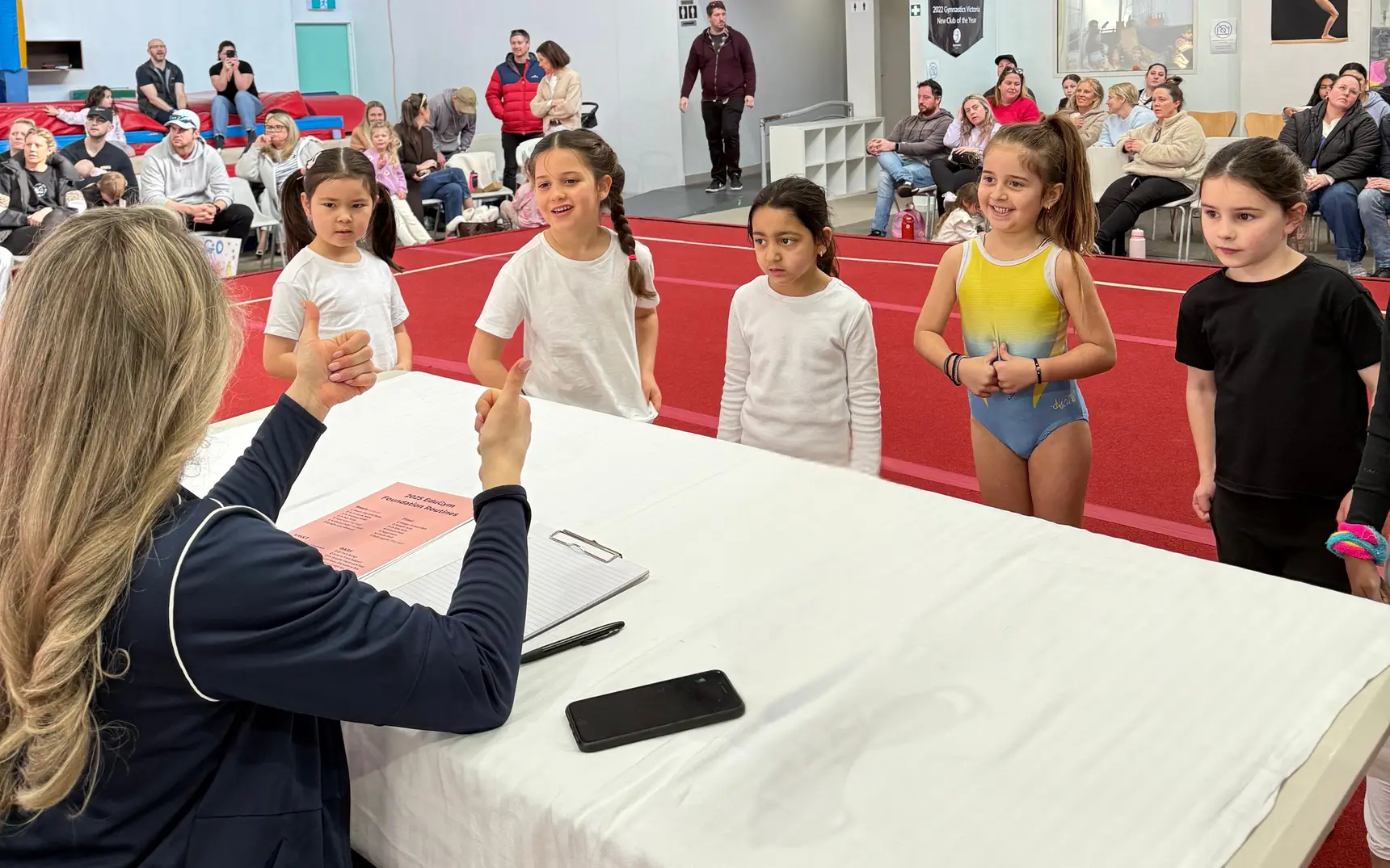 A judge giving a thumbs up to a line of gymnasts waiting to start their routines