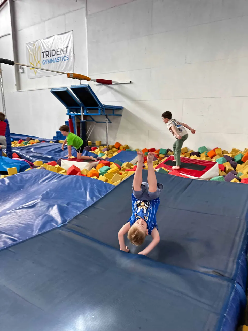 A young athlete rolling out of a skill onto a landing mat beside the foam pit