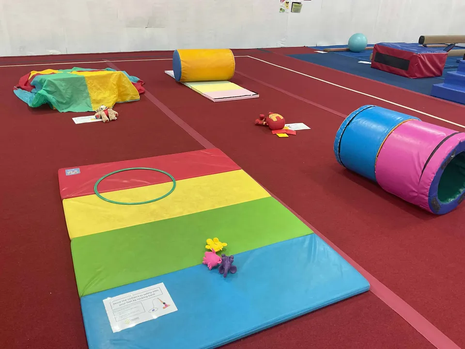 A JuniorGym obstacle course laid out with rainbow mats, hoops and soft rollers